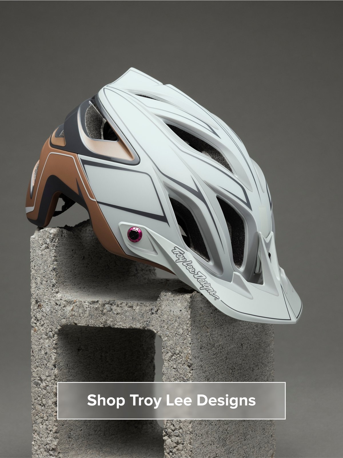 A helmet sits on a cinder block. Button reads: Shop Troy Lee Designs