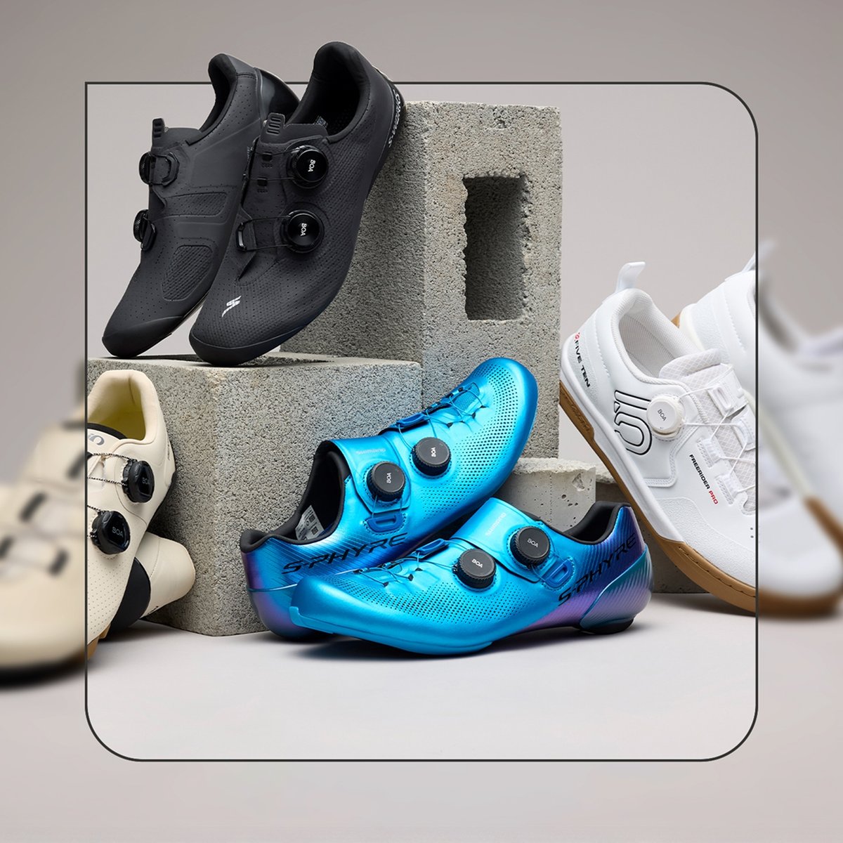 Four pairs of cycling shoes lean against cinder blocks.