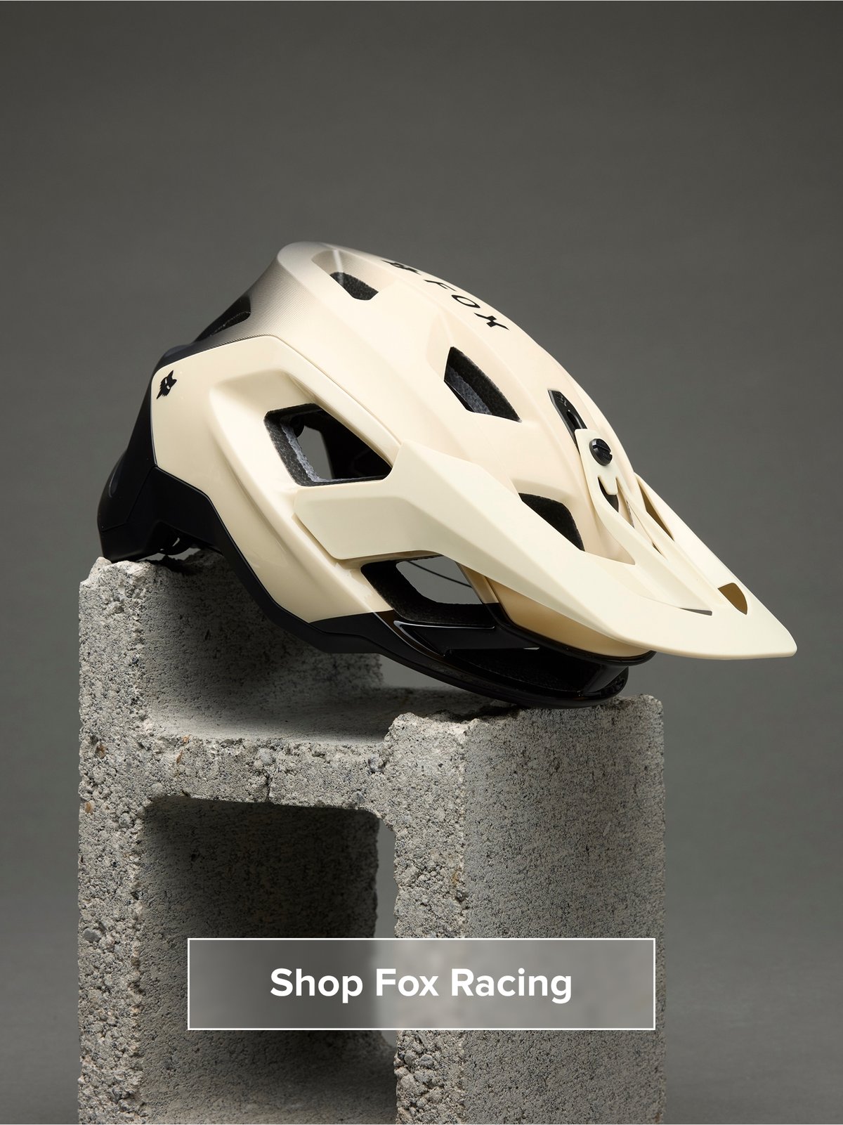 A helmet sits on a cinder block. Button reads: Shop Fox Racing