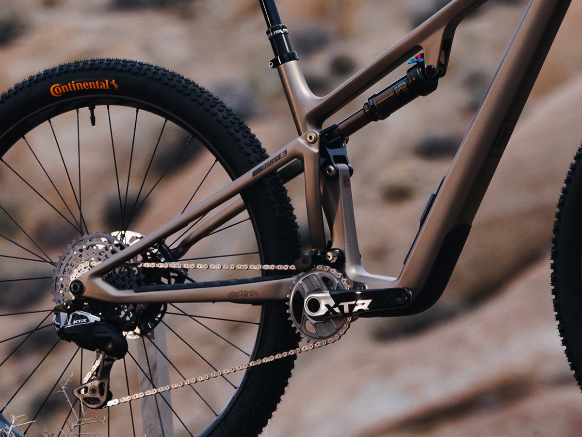 Frame detail showing the bottom bracket, chainring, rear suspension linkage, and shock.