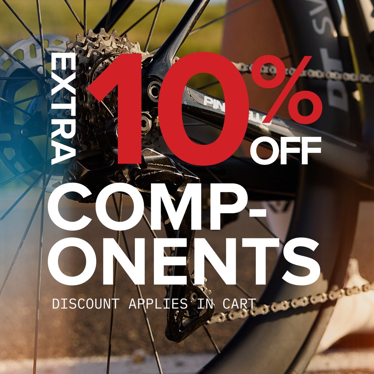 A close-up of a bicycle's rear wheel and derailleur, with overlaid text that reads: "Extra 10% off components. Discount applies in cart."