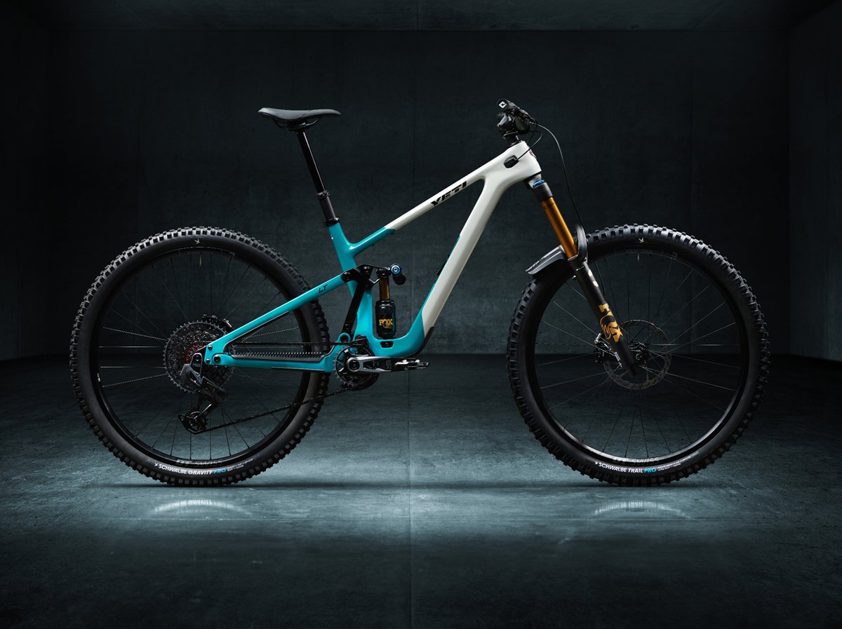 A teal and white mountain bike in a stark studio.